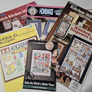 May include: A collection of six cross-stitch pattern booklets featuring kitchen-themed designs. Titles include Quick Kitchen Stitchin, Homemade, Kitchen Stitchin, Kitchen Potpourri II, Bobbie G. Designs My Kitchen, and tiny modernist Bake the World a Better Place.