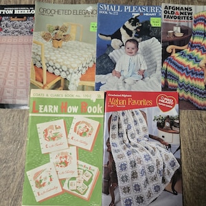 May include: A collection of vintage crochet pattern books. Titles include "Cotton Heirloom," "Crocheted Elegance," "Small Pleasures," "Afghans Old & New Favorites," and "Learn How Book." The books feature colorful crochet projects.