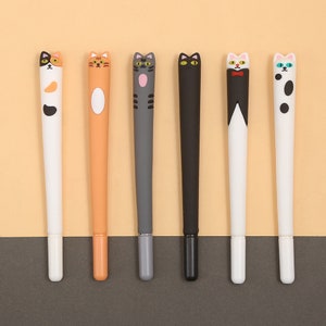 May include: Six colorful cat-shaped pens with different designs. The pens are white, orange, gray, black, white with a bow tie, and white with black spots.