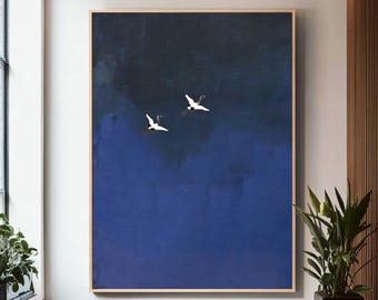 Könnte beinhalten: Ein großes rechteckiges Wandbild mit zwei fliegenden weißen Kranichen vor einem Hintergrund mit Farbverlauf in tiefem Marineblau und dunklem Indigo. Das Gemälde ist in einen dünnen hellen Holzrahmen gefasst und zeigt einen glatten Übergang.