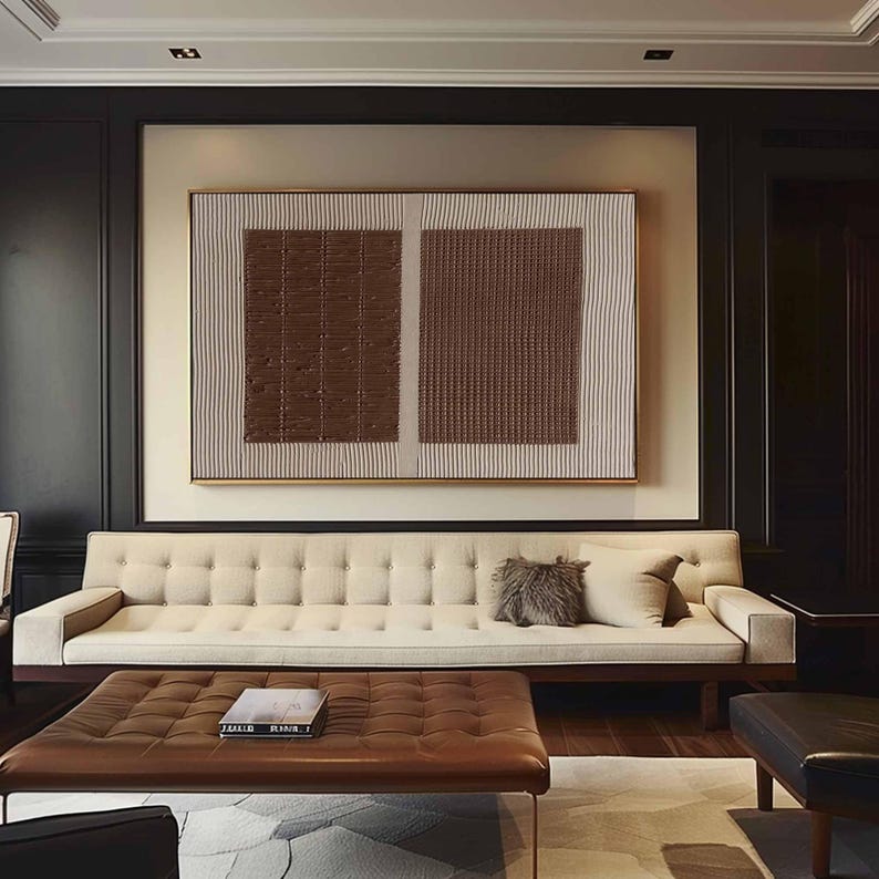 Puede incluir: Sal&oacute;n moderno con un sof&aacute; beige con mechones, una mesa de centro de cuero marr&oacute;n y una gran obra de arte abstracta. La obra de arte tiene dos cuadrados texturizados marrones y un fondo beige. La habitaci&oacute;n tiene detalles en madera oscura y una paleta de colores neutros.