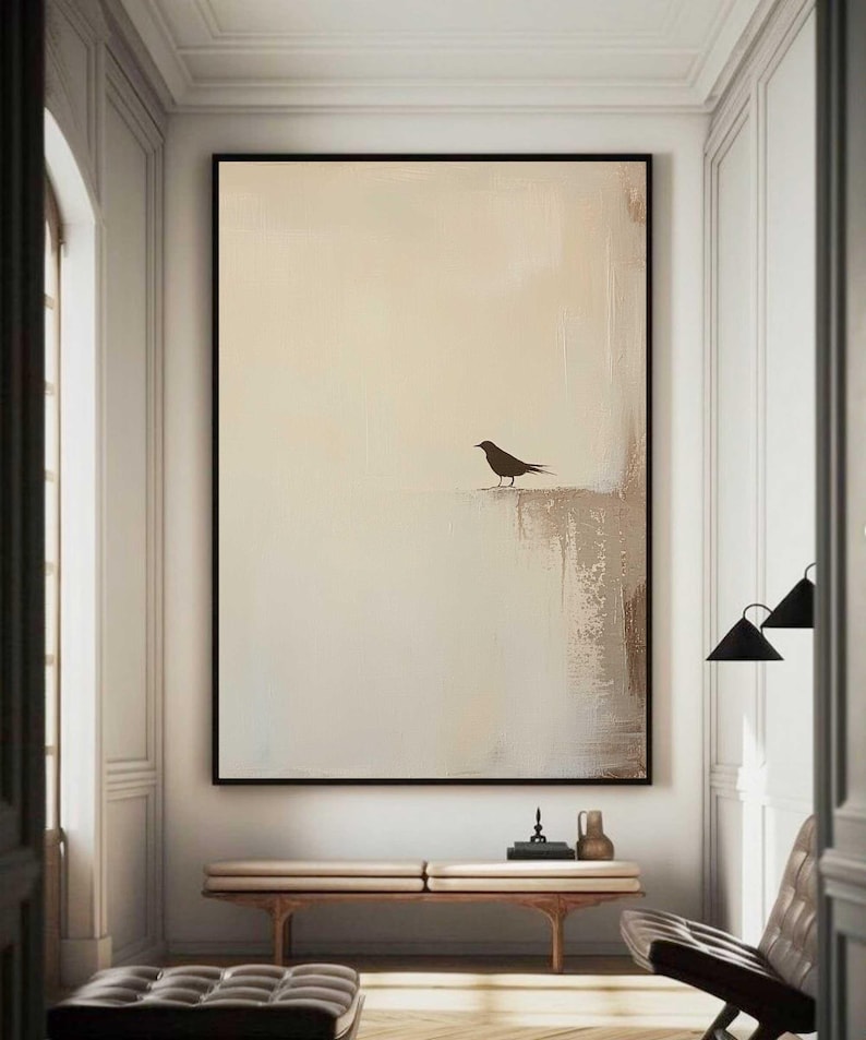 May include: A minimalist abstract painting with a single black bird silhouette on a beige background. The painting is framed in black and hangs on a white wall.