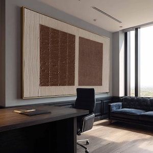 Puede incluir: Gran obra de arte abstracto con marco dorado. La obra presenta un dise&ntilde;o texturizado con cuadrados marrones y rayas verticales crema. Cuelga en una oficina moderna con un escritorio y un sof&aacute; azul.