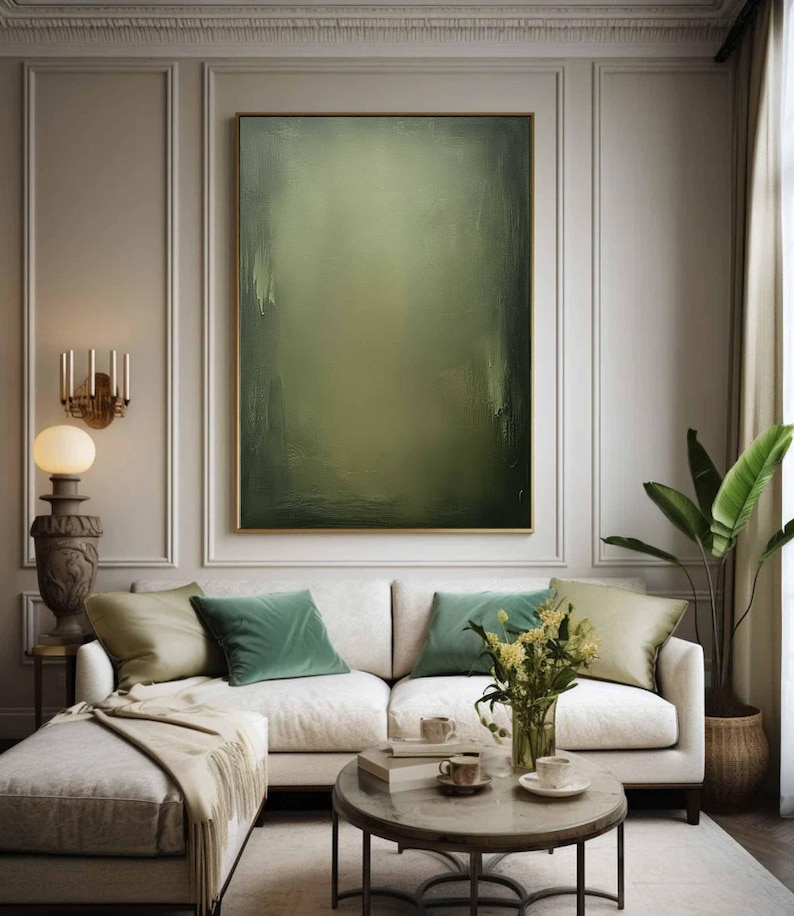 May include: A white sectional sofa with green velvet throw pillows in a living room with a large abstract painting in muted green tones, a coffee table with a vase of flowers, and a potted plant.