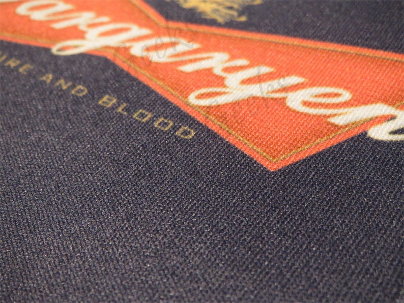 May include: A close-up of a navy blue fabric with the words "Fire and Blood" and "Stranger" in white lettering on a red background.
