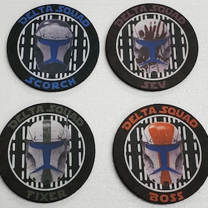 Puede incluir: Cuatro posavasos redondos negros con rayas blancas y grises. Cada posavasos presenta un casco de soldado clon de Star Wars diferente con una visera azul. El texto "DELTA SQUAD" está impreso en blanco en cada posavasos. Los nombres "SCORCH", "SEV", "FIXER" y "BOSS" están impresos en blanco en cada posavasos.