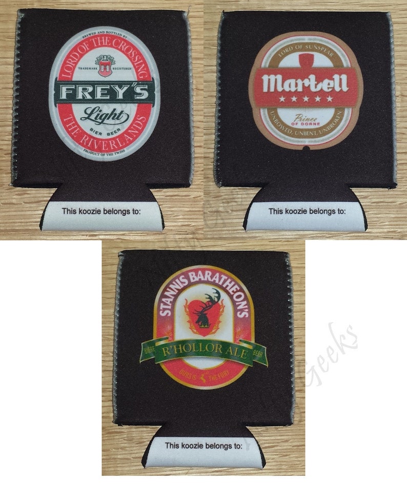 May include: Three black and white can koozies with different designs. The first koozie features a circular logo with the text "Frey's Light" and "The Riverlands". The second koozie features a circular logo with the text "Martell" and "Prince of Dorne". The third koozie features a circular logo with the text "Stannis Baratheon's" and "R'hollor Ale".