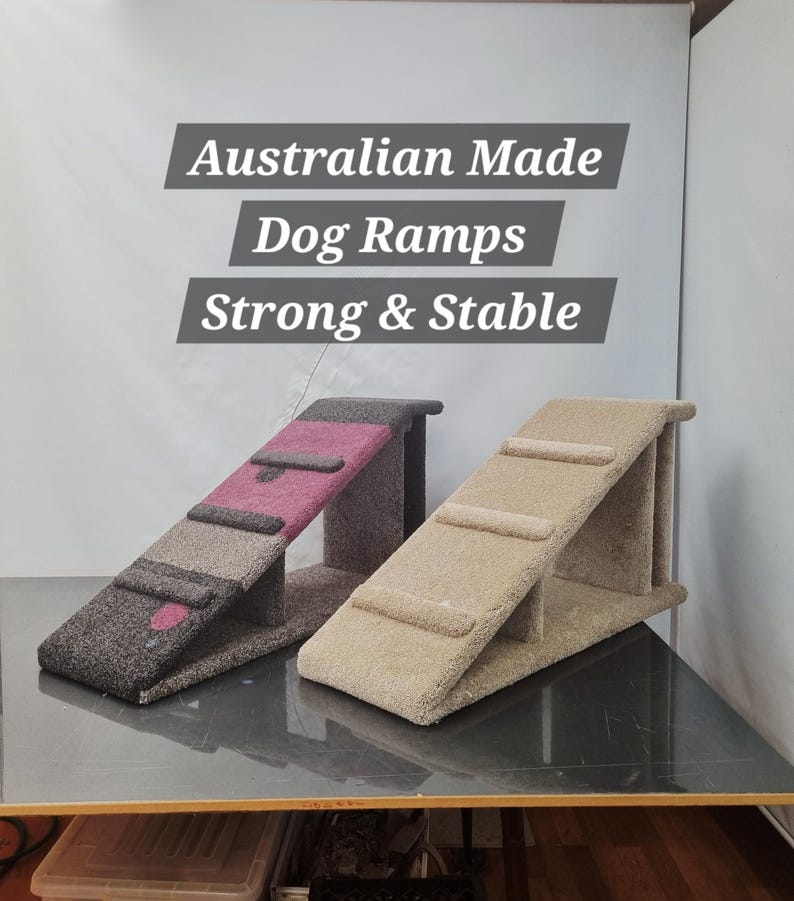 Puede incluir: Dos rampas para perros con superficies alfombradas. Una rampa es principalmente gris oscuro con un acento rosa, y la otra es beige. Las rampas tienen un dise&ntilde;o de escal&oacute;n y est&aacute;n etiquetadas como "Australian Made Dog Ramps Strong & Stable."