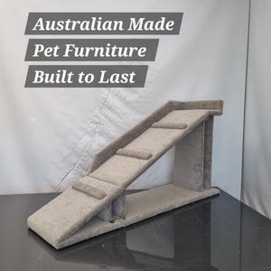 Puede incluir: Una rampa gris para mascotas con tres escalones y un dise&ntilde;o inclinado. La rampa est&aacute; hecha de un material suave similar a una alfombra y est&aacute; dise&ntilde;ada para mascotas. El texto en la imagen dice: Australian Made Pet Furniture Built to Last.
