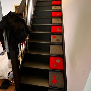 May include: Black painted wooden staircase with red and grey carpet runners on each step.