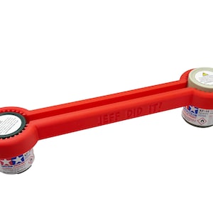 May include: Red plastic tool with the words "JEF DID IT!" printed on it. The tool is designed to open paint cans and has two circular openings on either end.