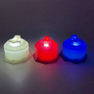 May include: Three 3D printed light-up buttons, one white, one red, and one blue. Each button has a different arrow symbol on top.