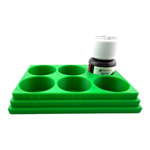 May include: A bright green plastic paint tray featuring five circular recessed wells for holding paint pots. One small Humbrol Dark Green Wash bottle with a white screw-top lid is placed inside the top right circular well of the tray.