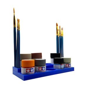 May include: A blue plastic paint rack with multiple paint pots and paint brushes. The paint pots are labeled with the brand "Tamiya" and "Lacquer Primer".