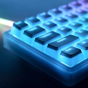 Puede incluir: Primer plano de un teclado mecánico retroiluminado con iluminación azul y púrpura. El teclado tiene teclas negras con letras blancas. Las teclas están iluminadas con un brillo azul brillante, creando una estética futurista. El teclado está diseñado para juegos o uso profesional.