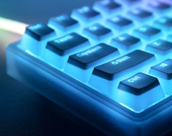 May include: Close-up of a backlit mechanical keyboard with blue and purple lighting. The keyboard has black keycaps with white lettering. The keys are illuminated with a bright blue glow, creating a futuristic aesthetic. The keyboard is designed for gaming or professional use.