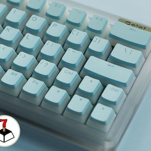 May include: Close-up of a mechanical keyboard with light blue and white keycaps. The keycaps have a two-tone design, with light blue tops and white sides. The keyboard has a clear, transparent frame. The keys include letters, numbers, and special function keys.