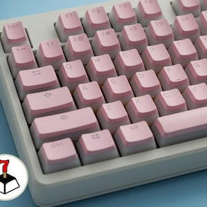 May include: A close-up of a computer keyboard with white keys and pink keycaps. The keys are arranged in a standard QWERTY layout. The keyboard has a light blue background.