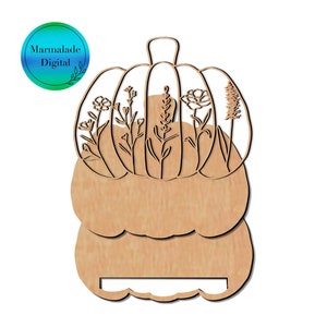 Op de afbeelding: Een houten uitsnijding van een pompoen met een steel en een decoratief ontwerp van bloemen en bladeren erin. De pompoen is gelaagd met een lege ruimte voor tekst.