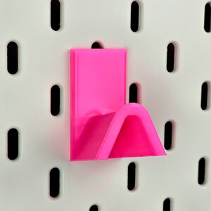 Pink glasses rack on white pegboard