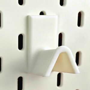 White spectacles rest on ikea pegboard