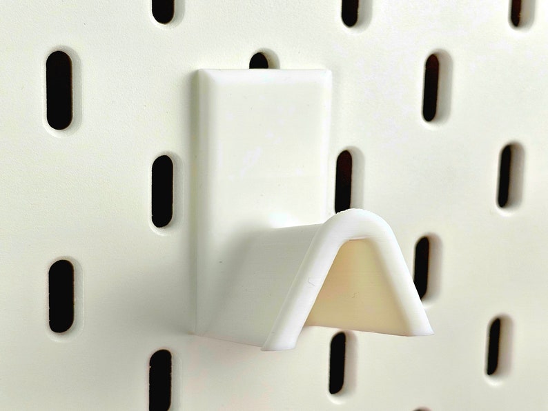 White spectacles rest on ikea pegboard
