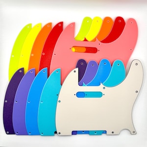 Könnte beinhalten: Eine Sammlung von Gitarren-Schlagbrettern, die fächerförmig angeordnet sind und ein Farbspektrum aus Neongelb, Orange, Rot, Pink, Lila, Blau, Türkis sowie einem cremefarbenen Stück an der Vorderseite aufweisen, jeweils mit vorgebohrten Schraublöchern.