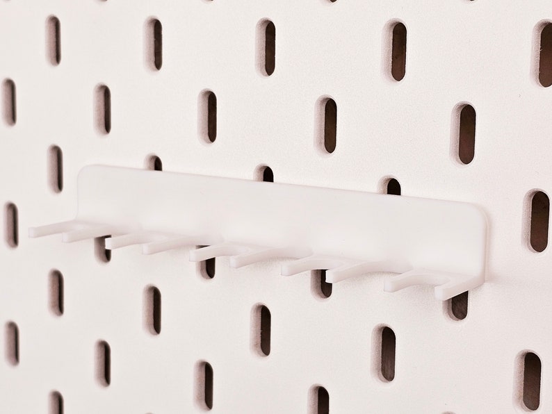 May include: White plastic pegboard hook with seven prongs. The hook is designed to hang on a pegboard.