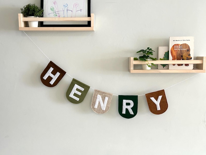 Custom felt name banner with scallop flags, strung on white twine, displayed on a nursery wall