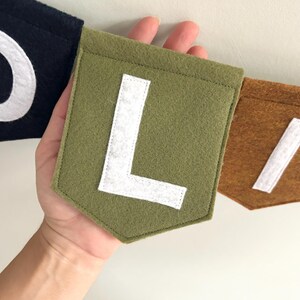 Close-up of hand-cut felt letters on customizable flag banner for baby name decoration