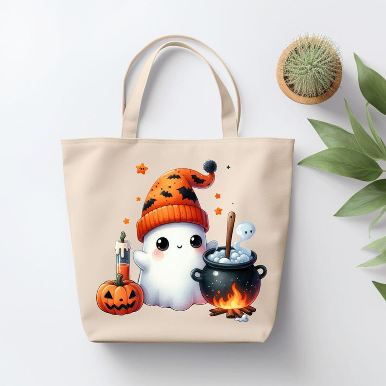 May include: A beige tote bag with a cute cartoon ghost wearing a orange and black hat and holding a cauldron with a small ghost inside. The ghost is surrounded by stars and a pumpkin.