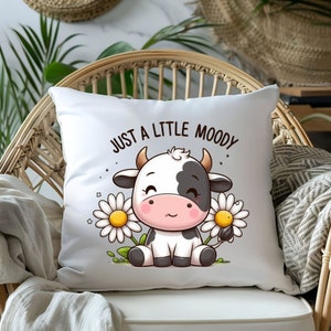 May include: White pillow with a cute cartoon cow with black spots and a daisy in each hand. The text "Just a little moody" is printed above the cow.