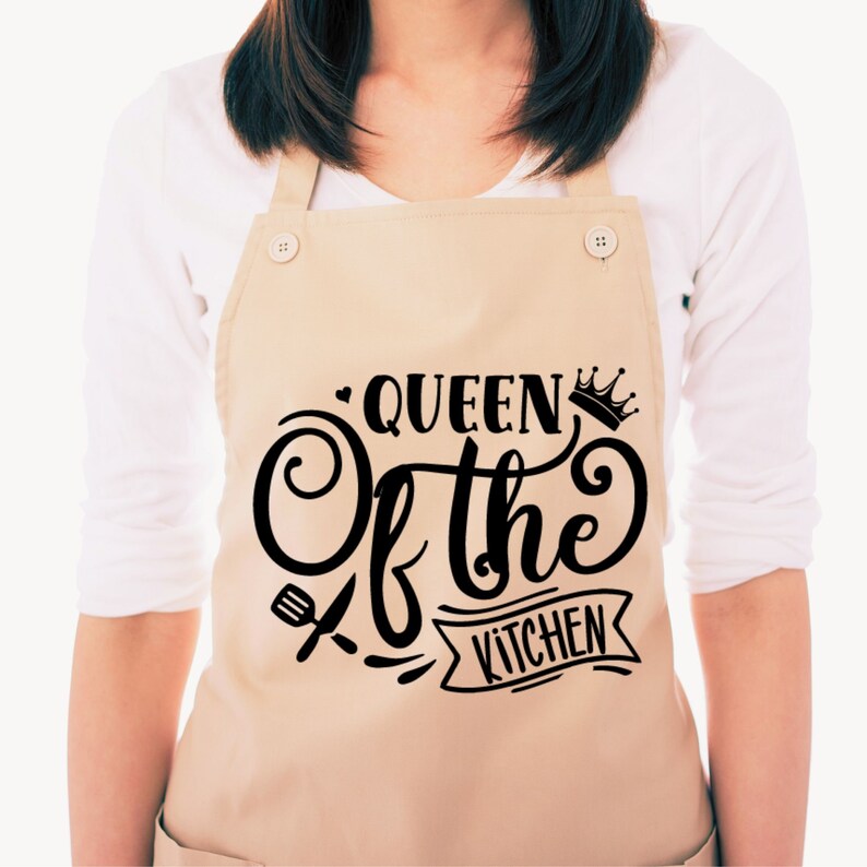 Może przedstawiać: Beżowy fartuch z czarnym napisem "Queen of the Kitchen" z koroną i grafiką trzepaczki i szpatułki.