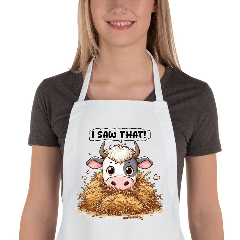May include: White apron with a cartoon cow peeking out of a pile of hay. The text "I saw that!" is above the cow.