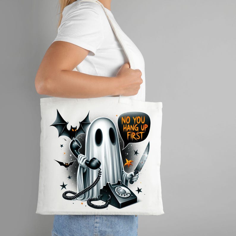 May include: White tote bag with a ghost holding a phone and a knife. The ghost is saying "No you hang up first".