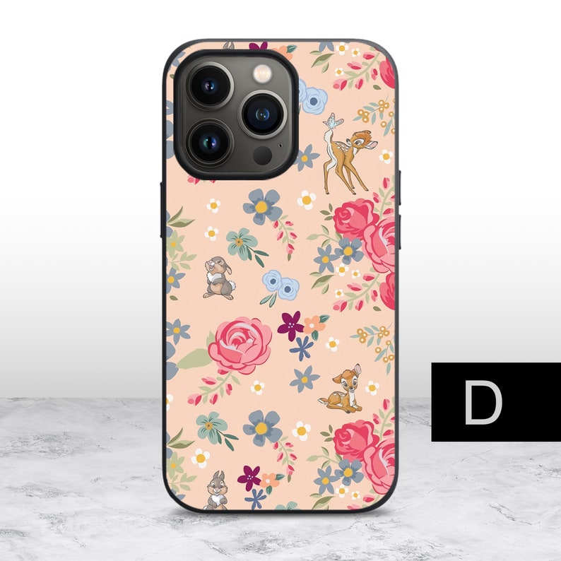 K&ouml;nnte beinhalten: Eine rosa und schwarze iPhone-H&uuml;lle mit einem Blumenmuster und Bildern von Bambi und Klopfer aus Disneys Bambi. Die H&uuml;lle hat eine schwarze Kamera-Erhebung mit drei Objektiven.