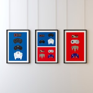May include: Three framed prints of different video game controllers. The left print is blue and features a white Nintendo 64 controller, a black Super Nintendo controller, and a black Sega Genesis controller. The middle print is blue and features a white Nintendo 64 controller, a black Super Nintendo controller, and a black Sega Genesis controller. The right print is red and features a purple Nintendo 64 controller, a gray Super Nintendo controller, and a black Sega Genesis controller.