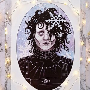 Peut inclure: Une illustration à l'aquarelle d'un personnage aux cheveux noirs et à la tenue noire, avec des flocons de neige qui tombent autour de lui. Le personnage a un teint pâle et des yeux sombres. L'arrière-plan est une aquarelle bleu clair et violette. L'illustration est signée "Sally B."