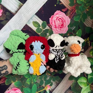 May include: Four crocheted plush toys inspired by characters from the film "The Nightmare Before Christmas". The toys are green, blue, black, and white.