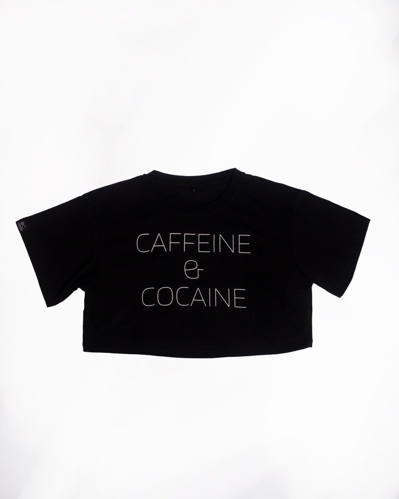 May include: Black cropped t-shirt with white text that reads "CAFFEINE & COCAINE".