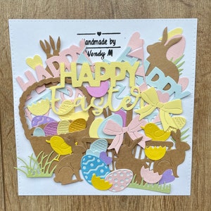 May include: A collection of colourful paper cutouts for Easter, including a basket filled with eggs, bunnies, chicks, and the words "Happy Easter".