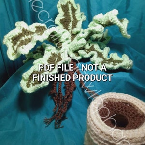 Op de afbeelding: Haakpatroon voor een groene en bruine bladplant met een bruin wortelstelsel en een beige pot. De tekst "PDF FILE - NOT A FINISHED PRODUCT" is zichtbaar op de afbeelding.
