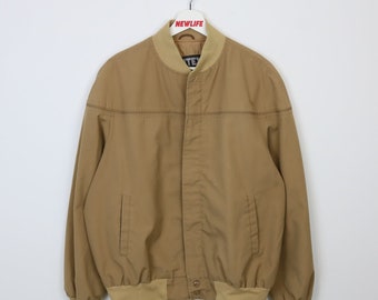 May include: A tan bomber jacket with a ribbed collar and cuffs. The jacket has a zipper closure and two pockets on the front.