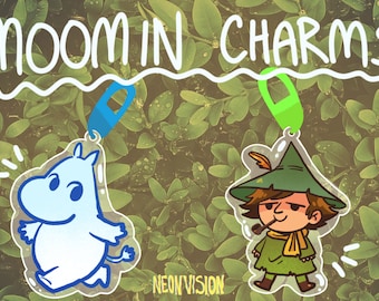 May include: Two Moomin character charms, one of Moomintroll and one of the Hattifatteners. The charms are clear acrylic with a white background and colorful cartoon illustrations. The charms are hanging from silver keychains.