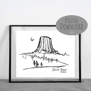 May include: Black and white line art illustration of Devils Tower National Monument in Wyoming. The illustration shows the tower with a crescent moon in the sky and trees in the foreground. The text "Devils Tower - WYOMING -" is below the tower.