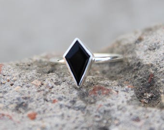 May include: A silver ring with a black diamond-shaped gemstone.