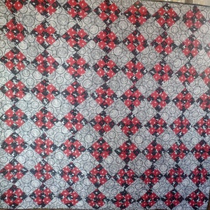 Könnte beinhalten: Eine rote und weiße Steppdecke mit einem Rautenmuster. Die Steppdecke ist aus Stoff mit einem sich wiederholenden Muster aus Kreisen und kleinen Tieren.