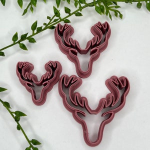 May include: Three pink plastic deer head cookie cutters of different sizes.