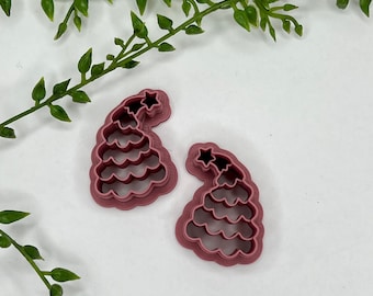 May include: Two pink plastic cookie cutters shaped like Christmas trees with a star on top.