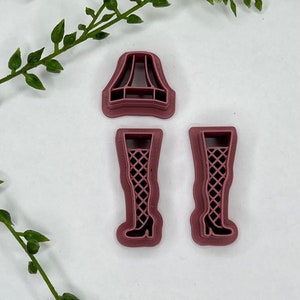 May include: Three pink plastic cookie cutters: a lampshade, and two pairs of legs with fishnet stockings.